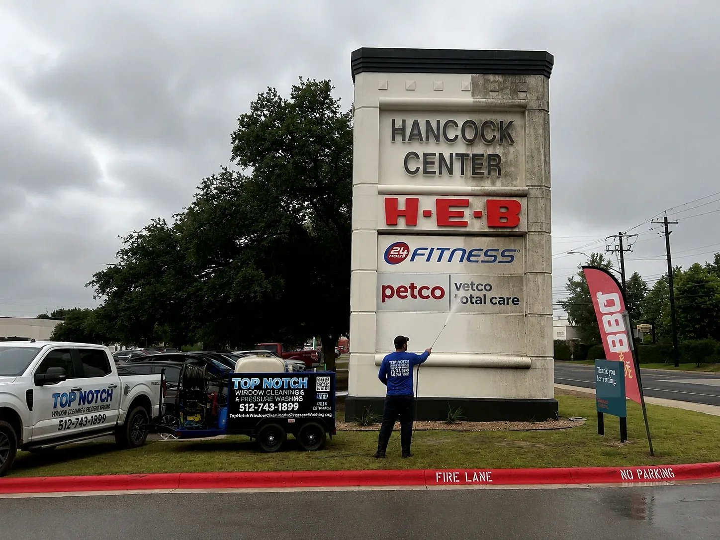 Top Notch cleaning Hancock Center sign with pressure washing equipment and wrapped truck in Austin TX